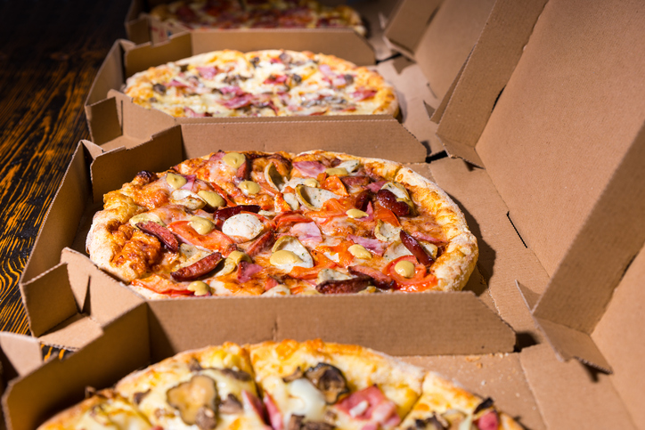 Close up of tasty pizzas with variety of toppings and cheese in cardboard take out boxes