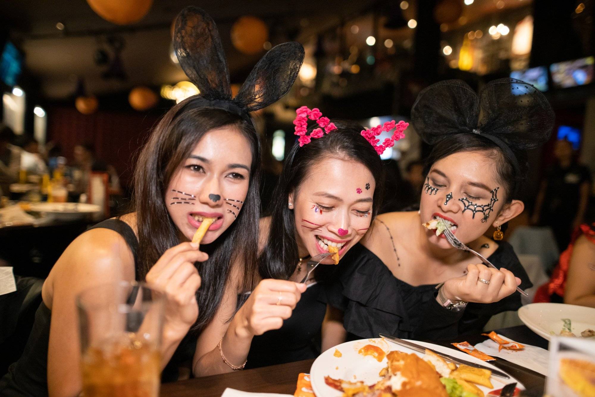 Asian women in halloween costume eating dinner at restaurant together Asian women in halloween costume eating dinner at restaurant together