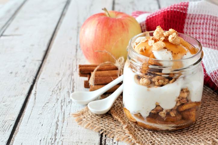 Baked apple parfait in a mason jar on white wood